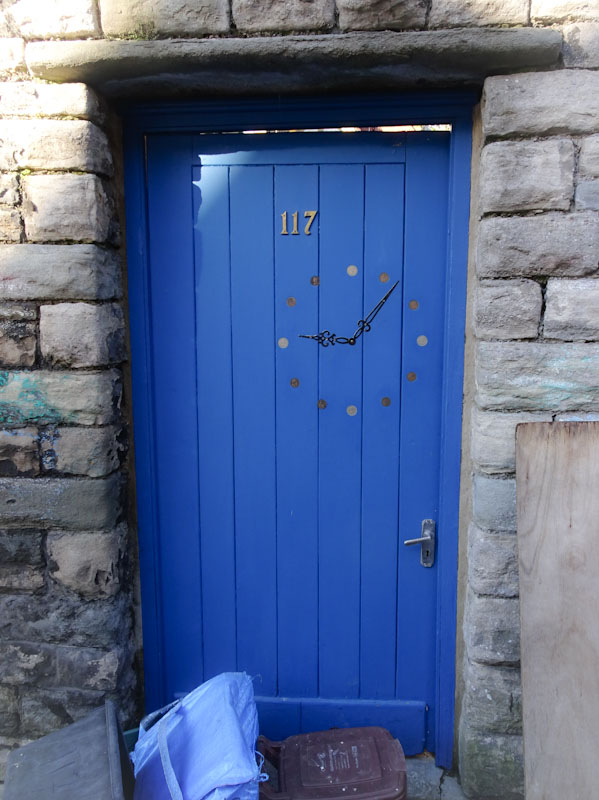 Blue door with a clock painted on it . Six past nine. Bristol, January 2021