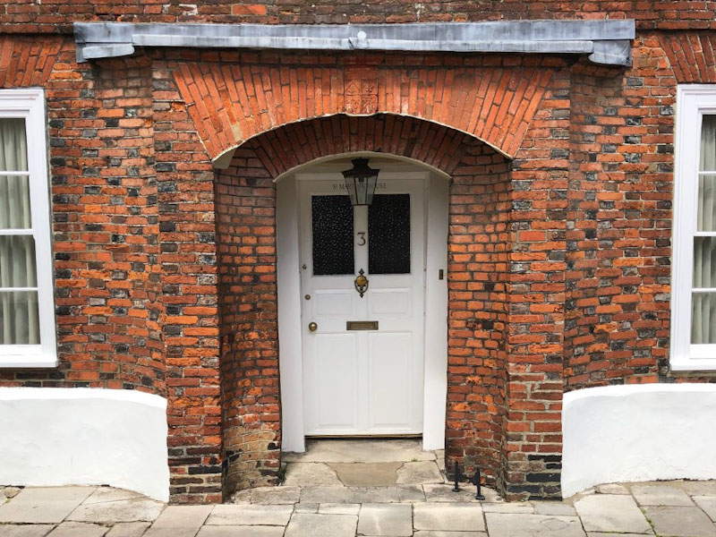 Door with beautiful brickwork including a crest above it, Chichester, May 2021