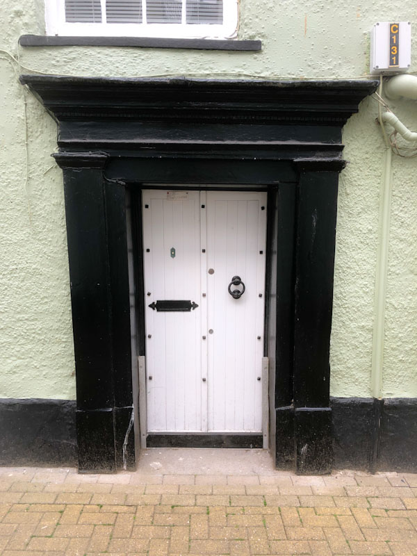 White door with flood gate slots on either side, Looe, Cornwall, October 2021