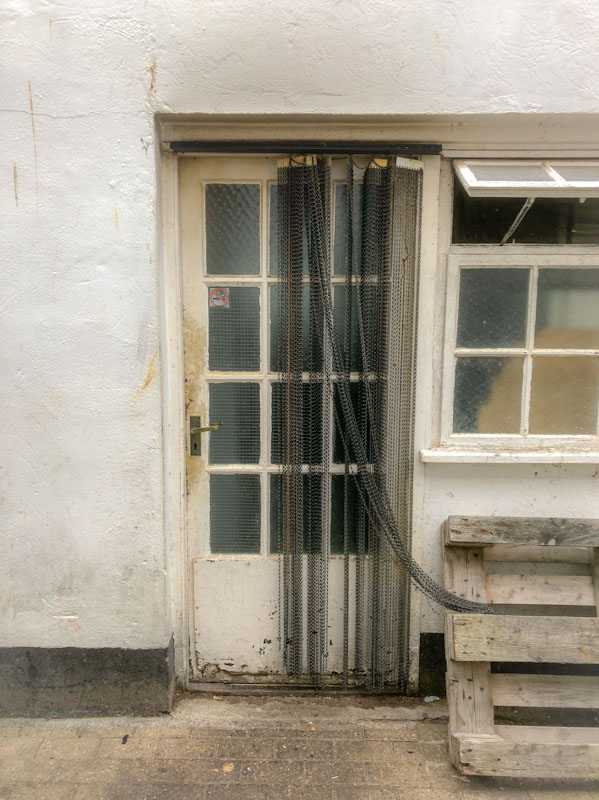Grubby back door with a chain curtain, Looe, Cornwall, October 2021