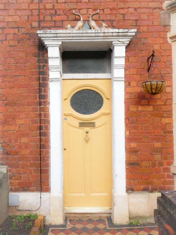 Yellow door with cats on the cornice, Greenbank, Bristol, February 2023