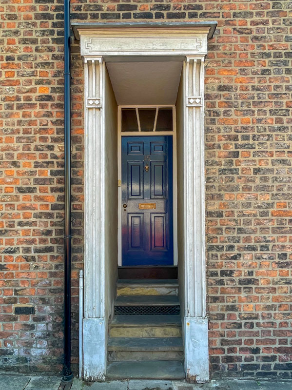 Recessed blue door with steps, York, June 2023