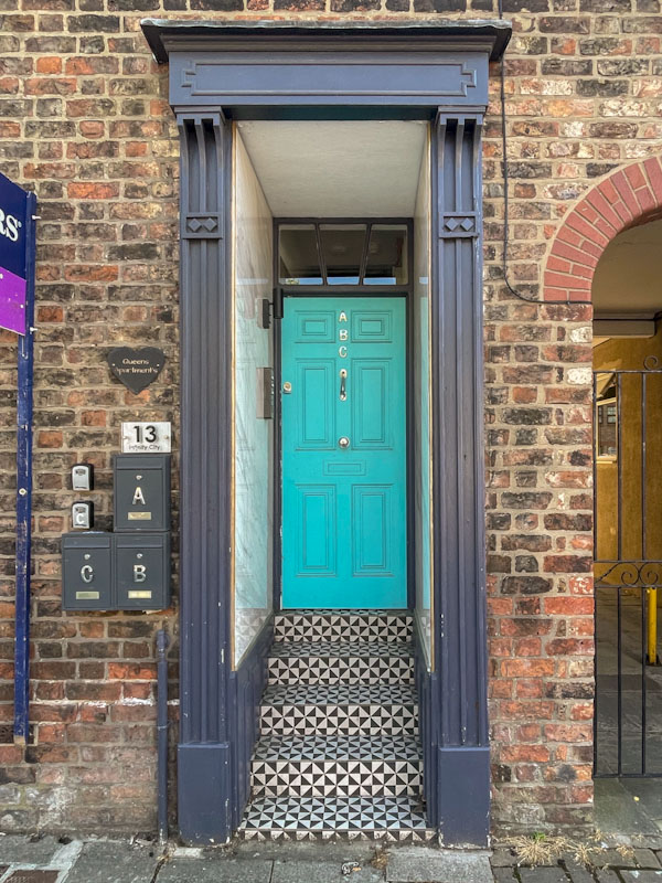 Recessed turquoise door with steps and tiles, York, June 2023