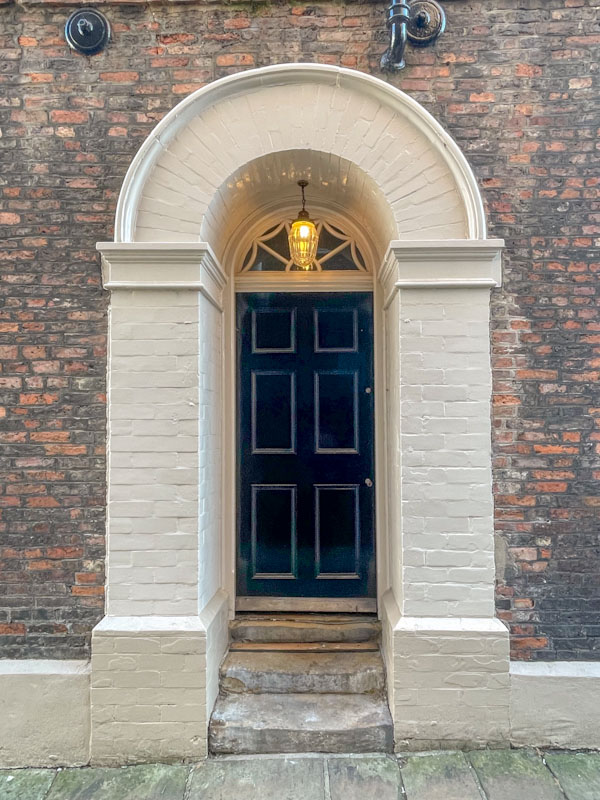 Thick brick arch surround and blue panelled door, York, June 2023