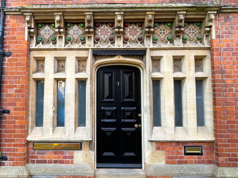 Fancy black door and windows, with tiled decorations above, Lincoln, July 2023