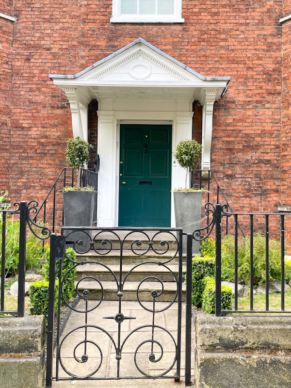 Grey-green door with portico and an iron garden gate, Lincoln, July 2023