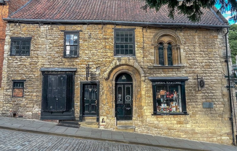 Three black doors on an old stone building and incredible windows, Lincoln, July 2023