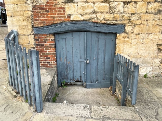Small grey cellar door and timber lintel, Lincoln, July 2023