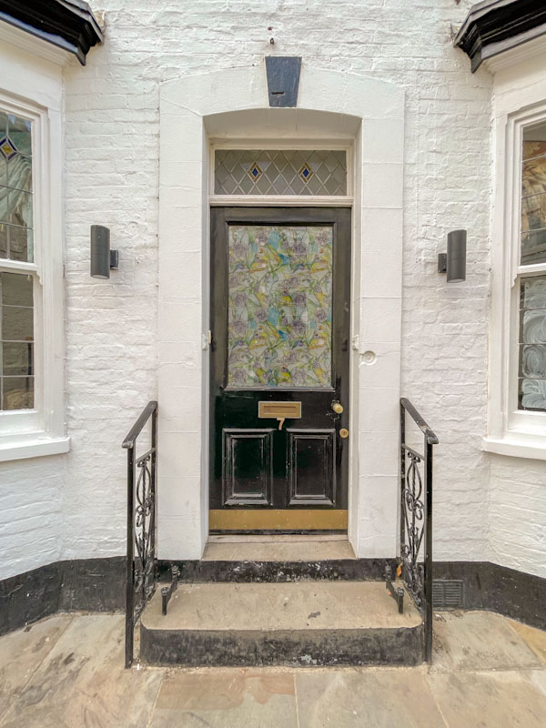 Black door with decorated glass and railings, Lincoln, July 2023