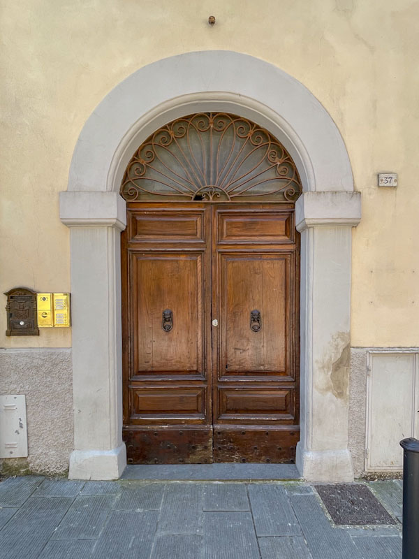Attractive wooden doors and iron work over the lunette window, Todi, Umbria, Italy, July 2023