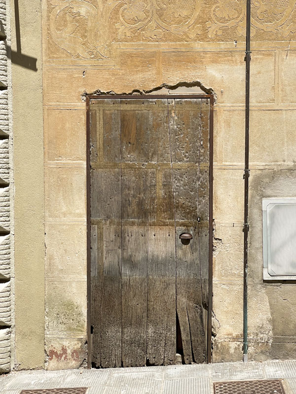 A well-used door and patterned render, Todi, Umbria, Italy, July 2023