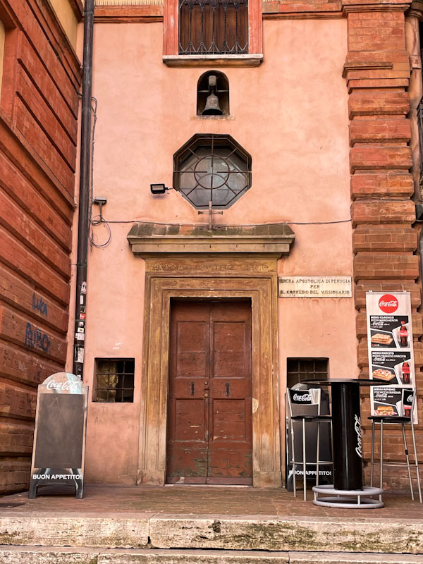 Door with wooden frame, window and bell, Perugia, Umbria, Italy, July 2023