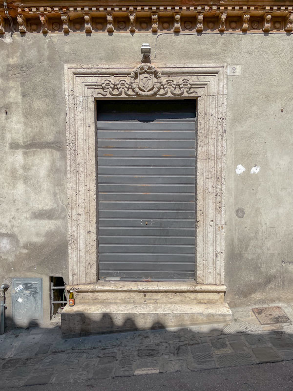Plain door with a fancy stone surround, Perugia, Umbria, Italy, July 2023