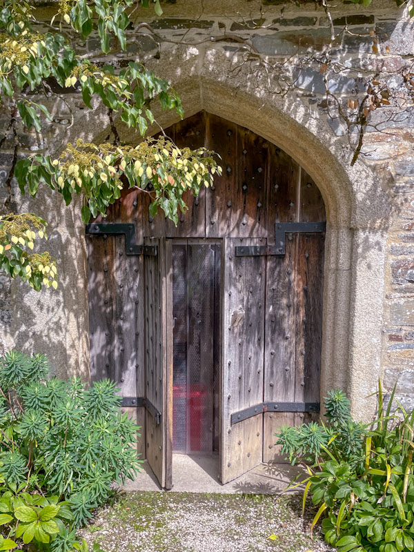 Out-building modern door in an old stone archway, Cotehele, Calstock, Cornwall, August 2023