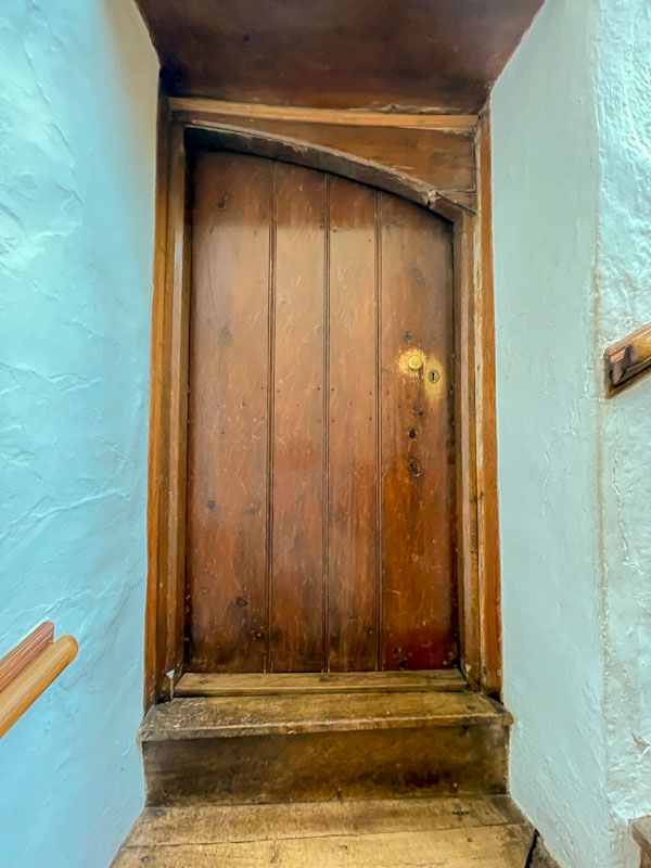 Landing door with curious frame and well worn keyhole and handle, Cotehele, Cornwall, August 2023