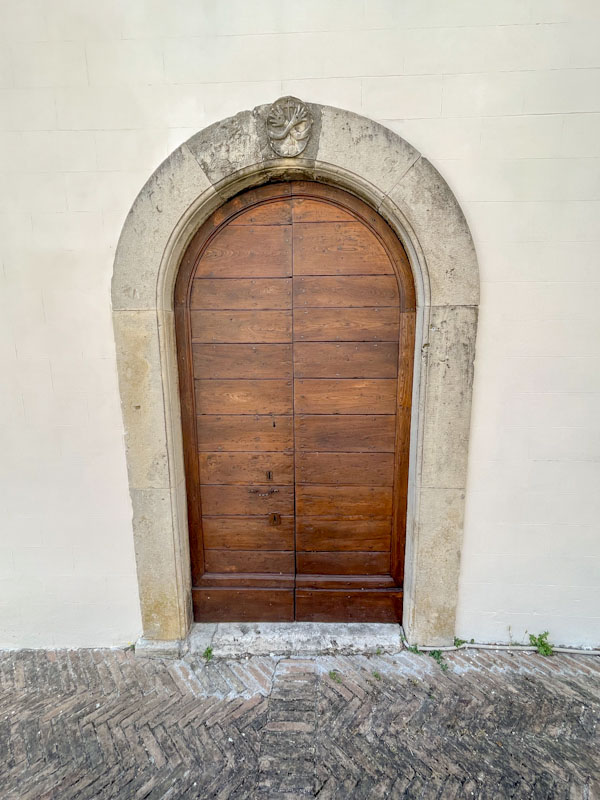 Arched door with stonework motif above, Montefalco, Umbria, Italy, July 2023