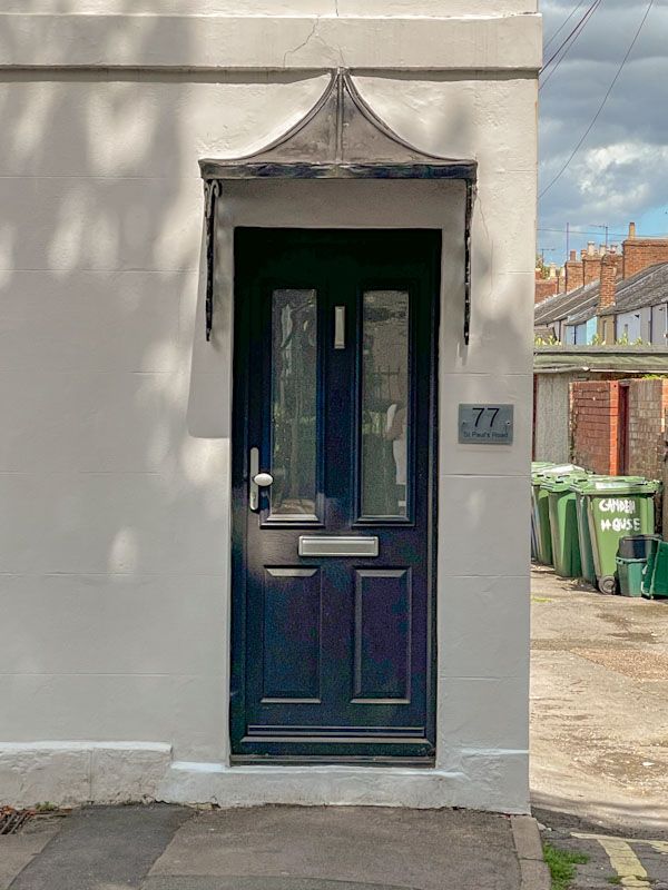 Ordinary black door with typically 'Cheltenham' awning, Cheltenham, July 2023