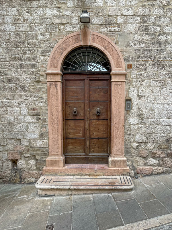 Fine arch surround and wooden door, Assisi, Umbria, Italy, July 2023