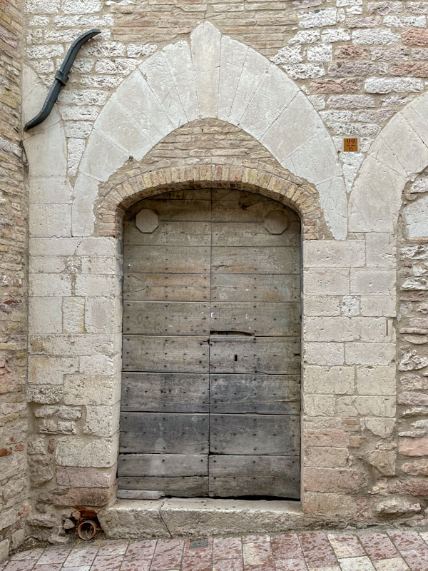 Wooden doors in an altered brick/stone doorway, Assisi, Umbria, Italy, July 2023