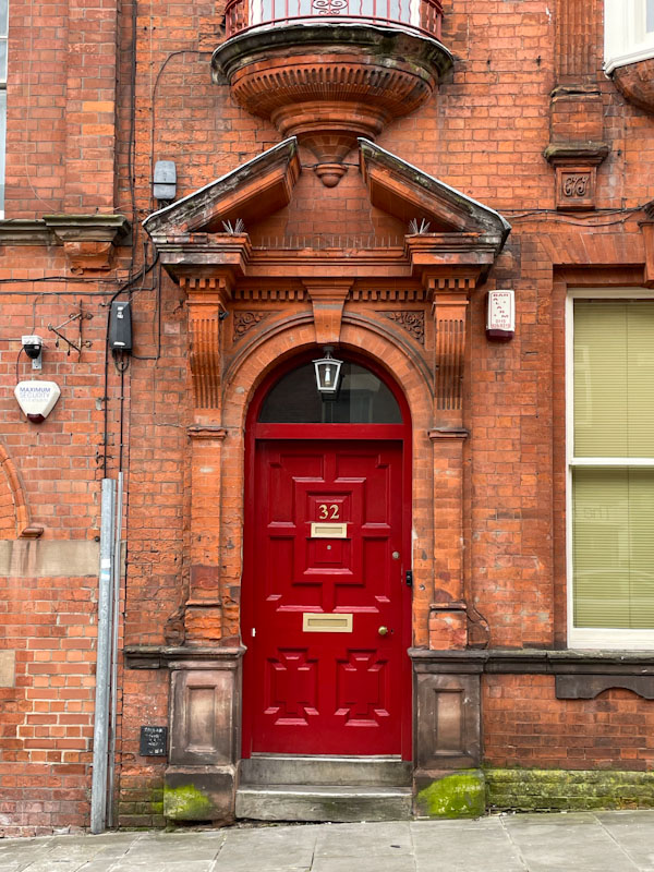 Red door with ornate panelling and stonework, Nottingham, March 2024