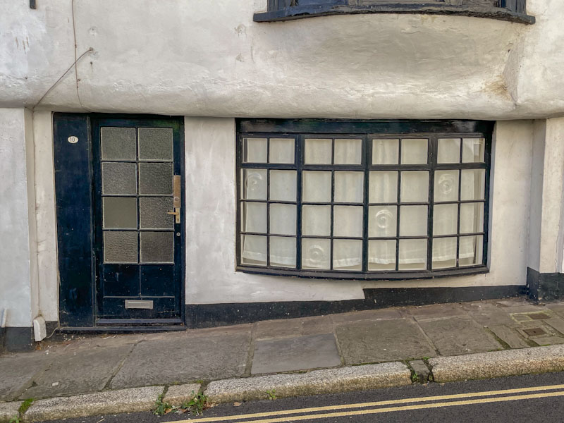 Black door with glass panels and old bay window, Exeter, October 2023