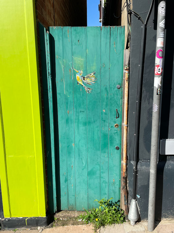 Blue gate with artwork from None Here, Exeter, October 2023