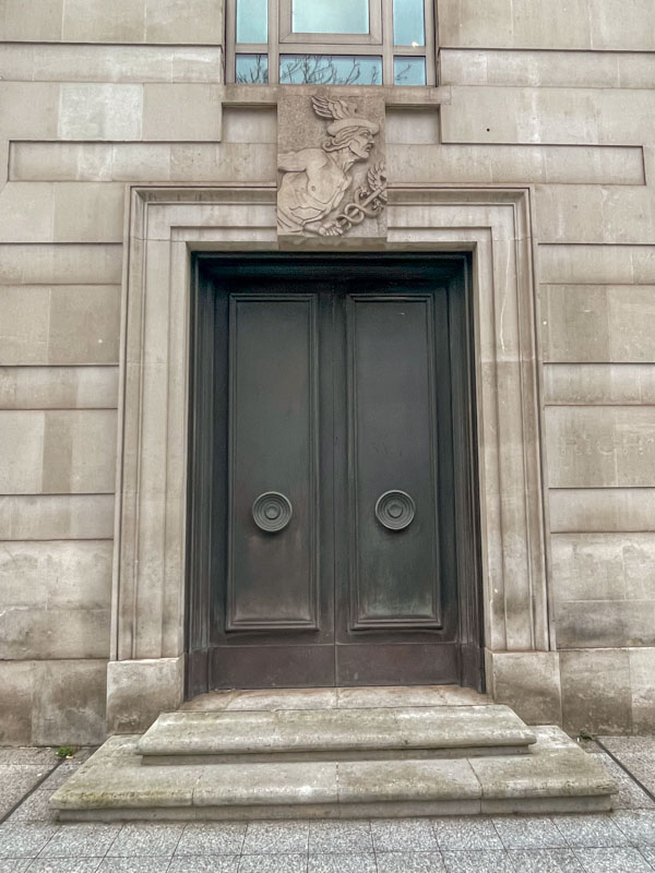 Austere doors with stone image of Mercury, Central London, March 2024