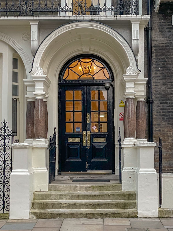 Black double doors and distinctive granite pillars, London, March 2024