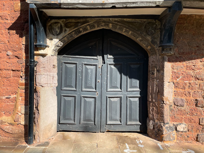 Black double doors in an ancient archway, Exeter, October 2024