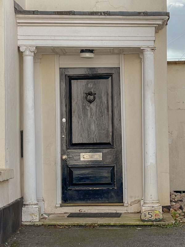 Black door with columns at number 5, Exeter, Devon, October 2023