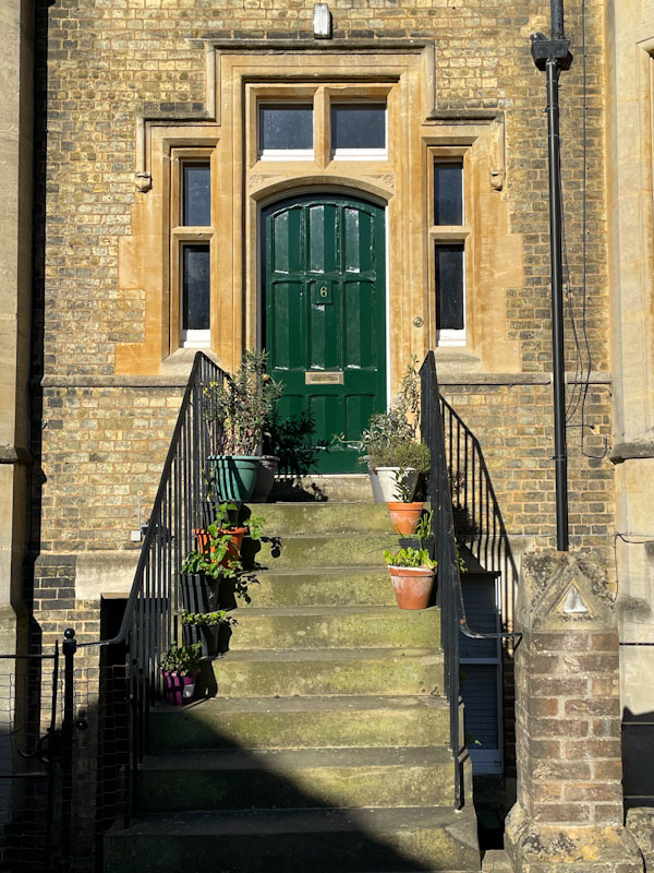 Black door and sturdy stone surround, steps and flower pots, Peterborough, April 2024