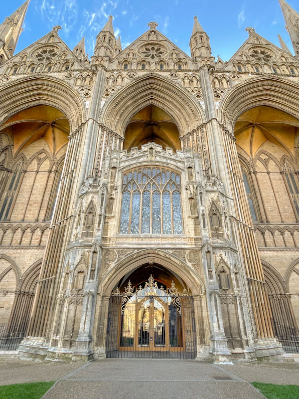 Wrought iron gate and glass doorway with large vaulted archways to Peterborough Cathedral, Peterborough, Cambridgeshire, April 2024