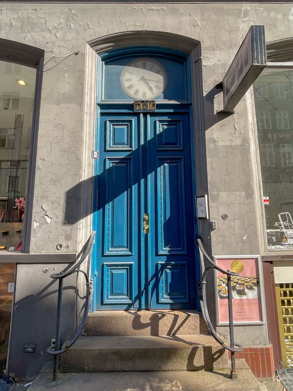 Blue door with a clock in the light fan, Bredgade, Copenhagen, Denmark, September 2024