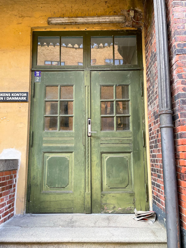 Green door and newspaper, Stokhusgade, Copenhagen, September 2024