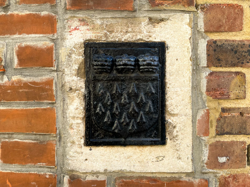 Black coat of arms embedded in a wall in Pound Lane, Godalming, Surrey, March 2025