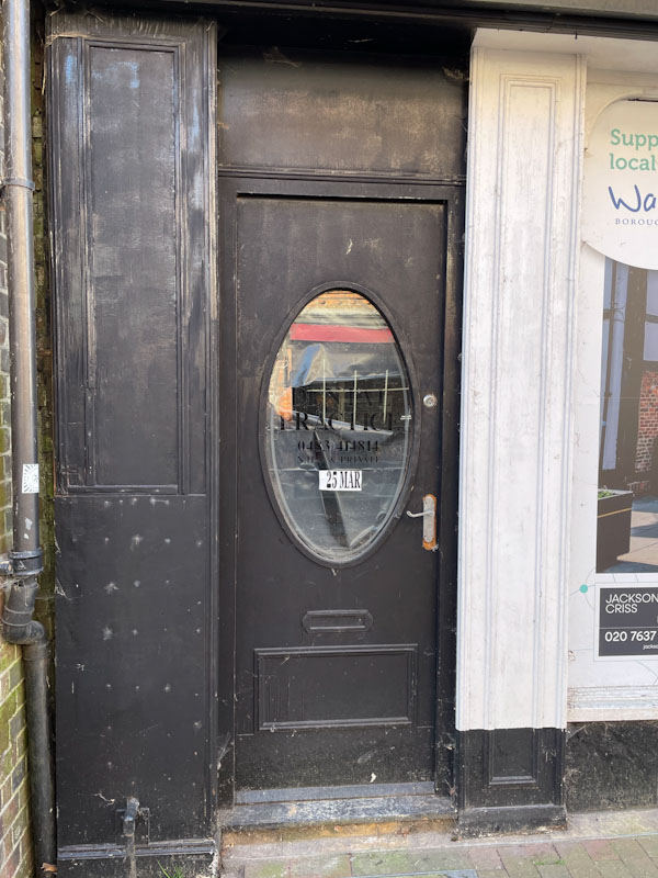 Black door with a large oval window, High Street, Godalming, Surrey, March 2025