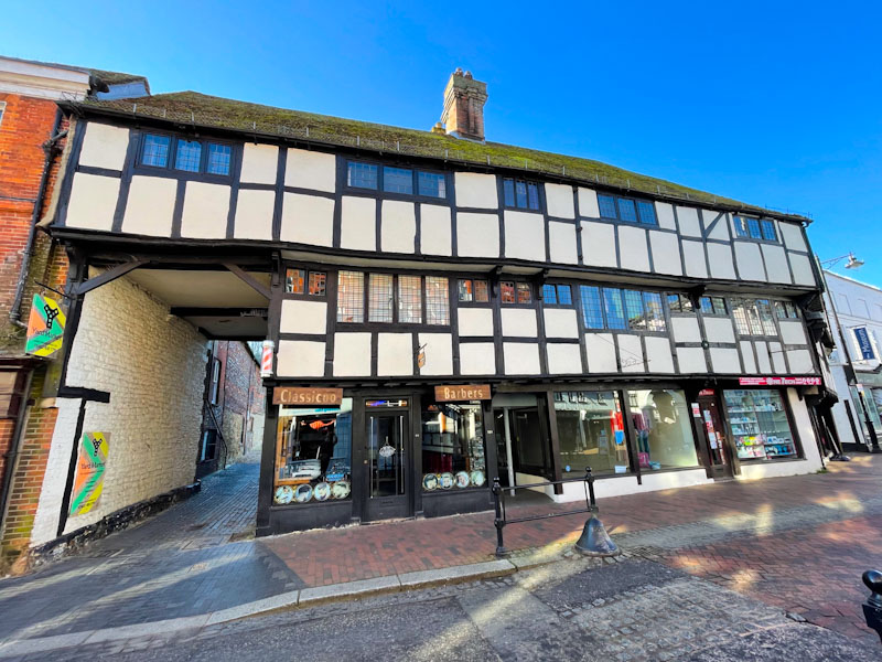 Large timber frame building with tiered floors and shop doors, High Street Godalming, Surrey, March 2025