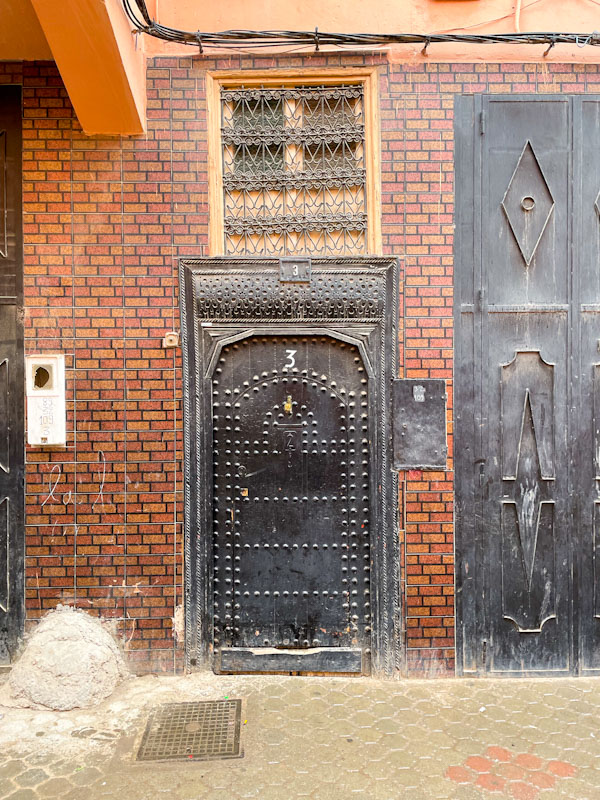 Studded black door with small window above, Tariq Sahrij Gnaoua, Marrakesh, Morocco, January 2025