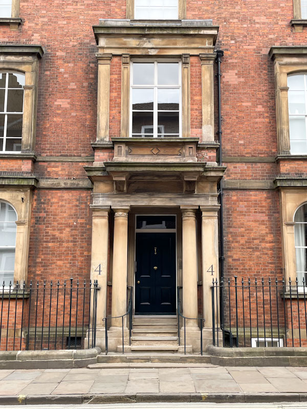 Columned portico entrance and black door, York, North Yorkshire, June 2024