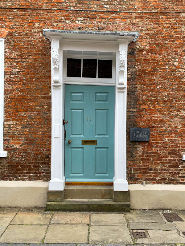 Teal door and wonky door frame, York, North Yorkshire, June 2024