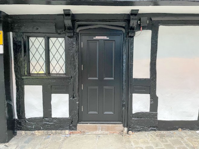 Modern black door set in a Tudor timber-framed building, Butcher Row, Shrewsbury, Shropshire, England, April 2026