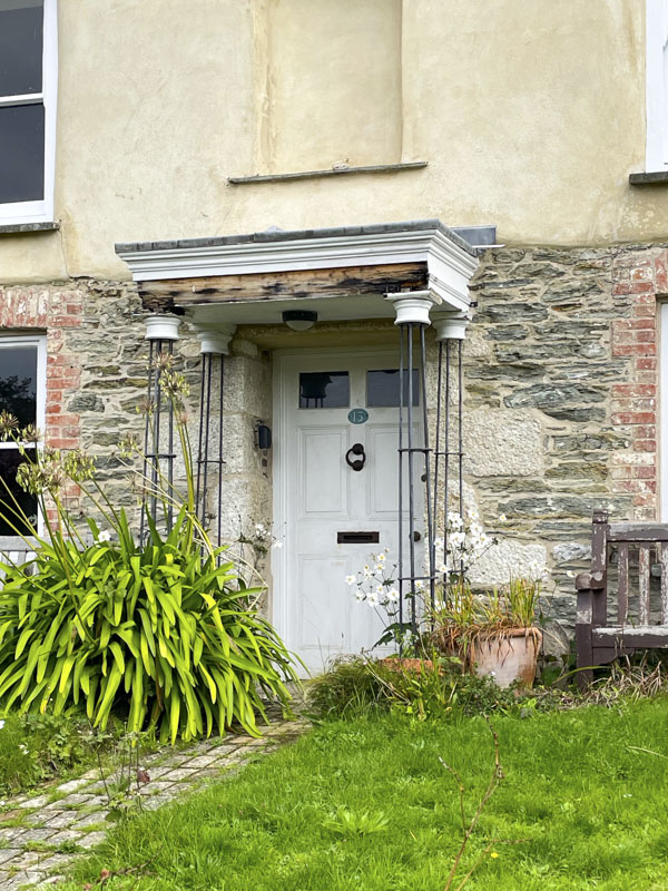 White door with rickety awning and statue bay above, Charlestown, Cornwall, October 2026