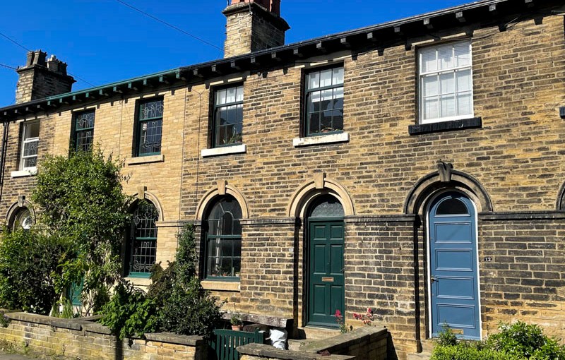 Black and blue doors in a terrace of houses, William Henry Street, Saltaire, West Yorkshire, England, May 2025