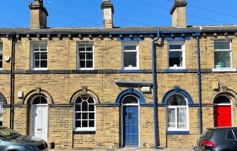 White, blue and red doors in a terrace, Titus Street, Saltaire, West Yorkshire, England, May 2025