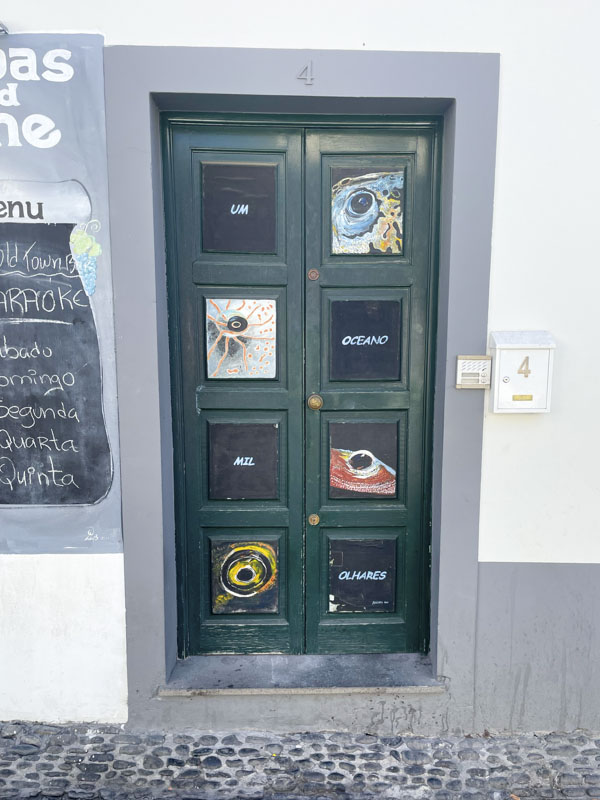 Panelled door with fish eyes painted in each panel, Travessa das Torres, Funchal, Madeira, September 2025