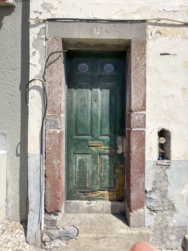 Weathered green door with two small portholes, Rua 31 de Janeiro, Funchal, Madeira, Portugal, September 2025