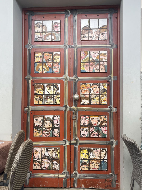 Door with many faces and painted bars, Rua de SantaMaria, Funchal, Madeira, Portugal, September 2025